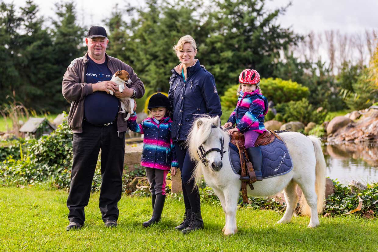 Fritz Schlubeck mit Hund Julchen, Christin Schlubeck und ihre beiden Töchter mit Mini-Pony auf der Wiese